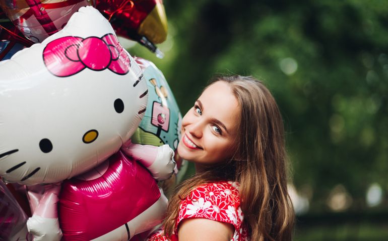 Young girl posing with balloons and holding hello kitty