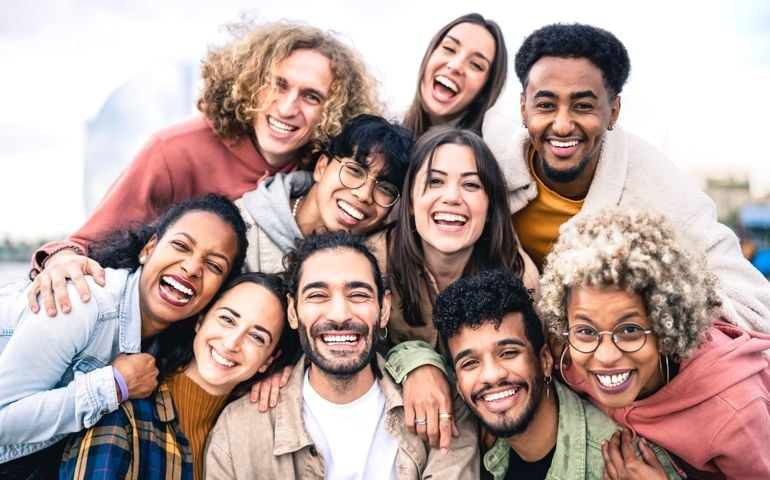 Multi ethnic guys and girls taking selfie outdoors with backlight - Happy life style friendship concept on young multicultural people having fun day together in Barcelona - Bright vivid filter