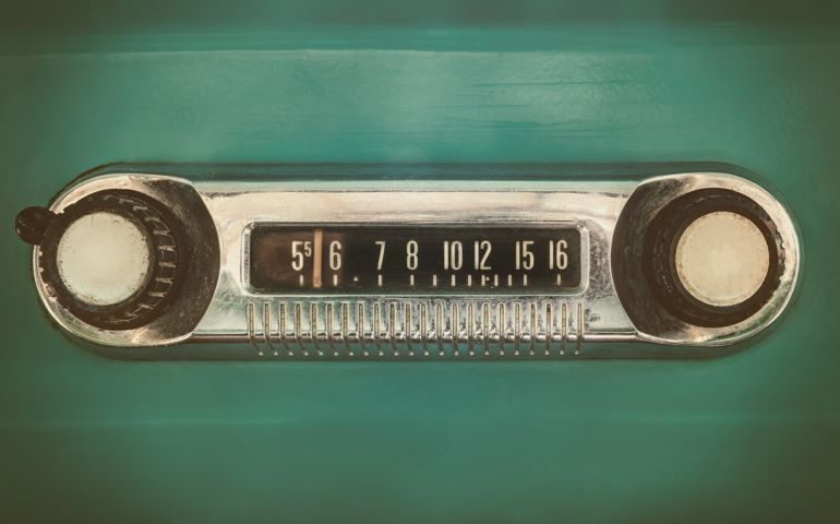 Retro styled image of an old car radio inside a green classic car
