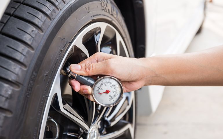 Close-Up Of Hand holding pressure gauge for car tyre pressure measurement