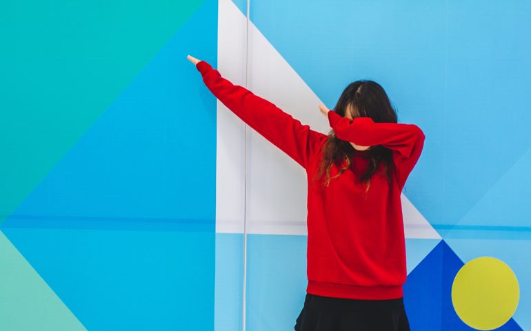 Woman Gesturing While Standing Against Blue Wall