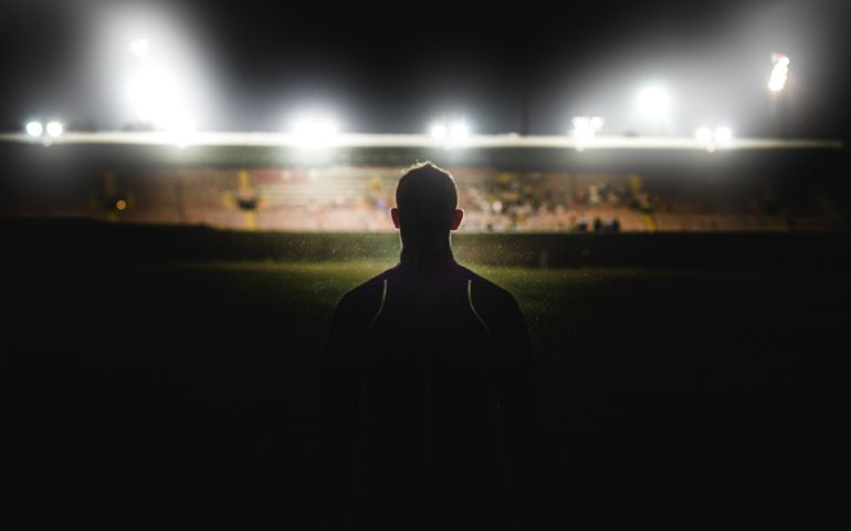 A young muscular Caucasian male walking in the rain at night in front of a stadium with stadium floodlights spotlights towards the competition near Cape Town South Africa