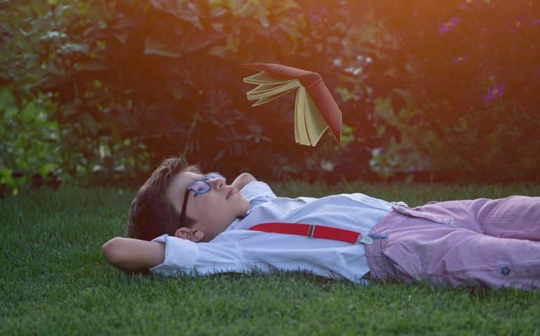 Child reading a book in back yard