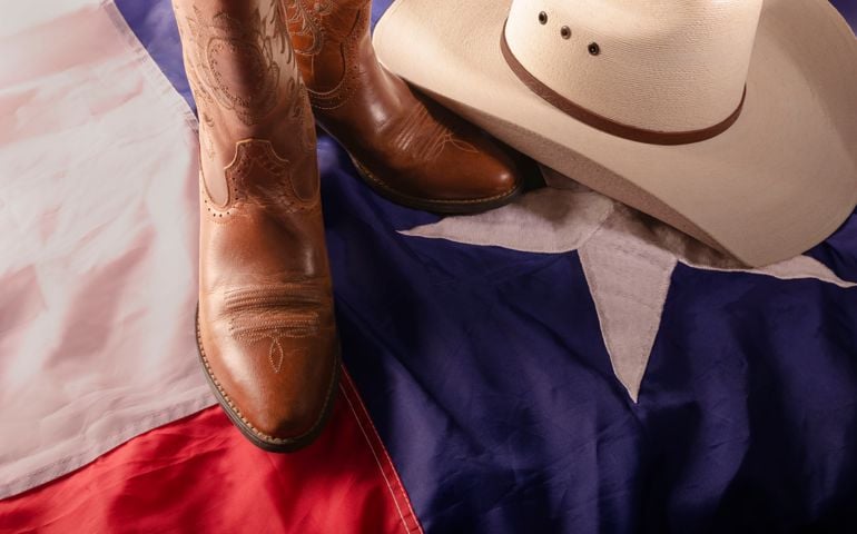 straw cowboy hat and cowboy boots surrounded by texas flag