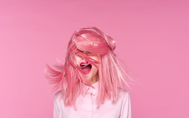 Woman on pink background with flying pink hair, portrait