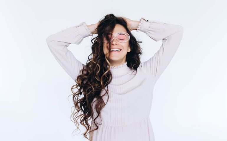 Portrait of a pregnant woman in pink glasses holding her belly on white background,