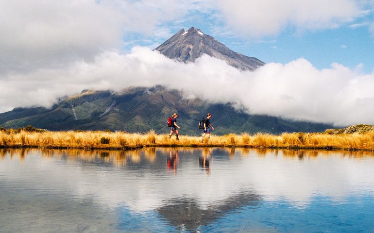 Hiker couple Reflection of Mount Taranaki Egmont in natural lake