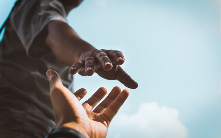 Help Concept hands reaching out to help each other in dark tone