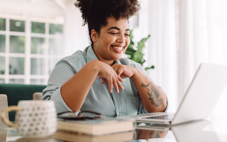 Positive woman video calling using laptop. Businesswoman teleconferencing on laptop while working from home.