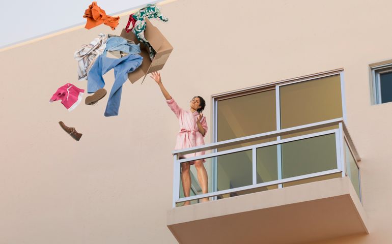 Mixed race woman throwing clothes off balcony