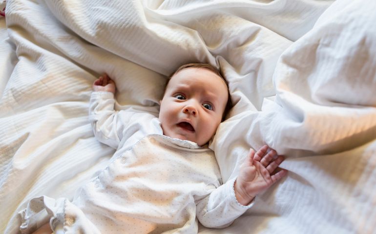 Caucasian baby gasping in bed