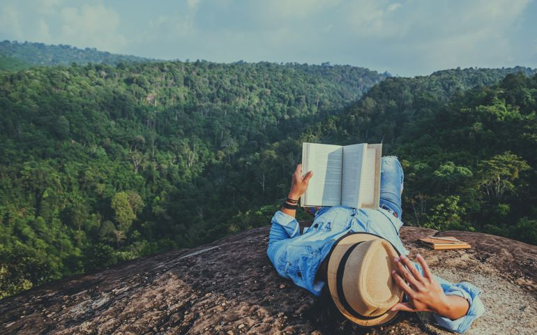 Asian man travel relax in the holiday. sleep relax read books on rocky cliffs. On the Moutain. In Thailand