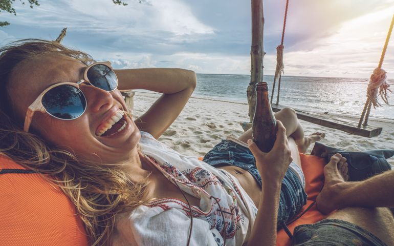 Personal perspective of relaxing on the beach with girlfriend and beer, feet view People travel vacations relaxation concept