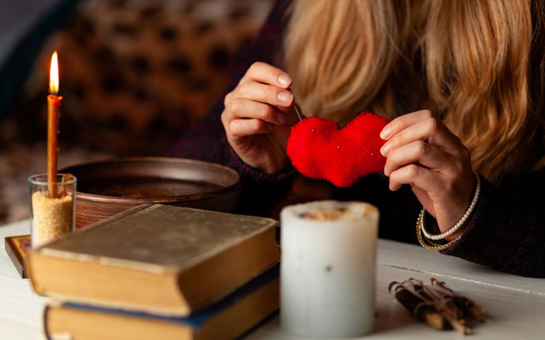 Red heart in hands of witch, love spell and broken heart, unrequited love. Psychic vision, fortune teller.