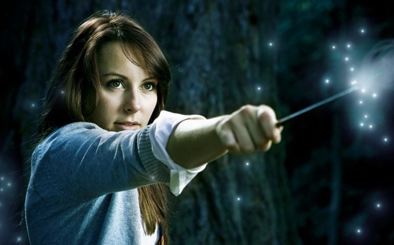 Teenage wizard girl with magic wand casting spells in a enchanted fantasy forest