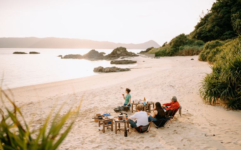 People enjoying barbecue on tropical beach at sunset, Amami Oshima Island, Kagoshima, Kyushu, Japan