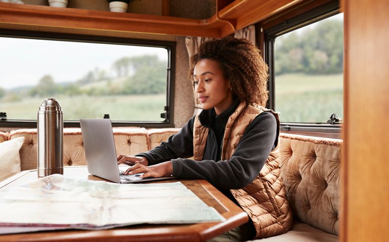 Young woman using laptop while sitting in camper van