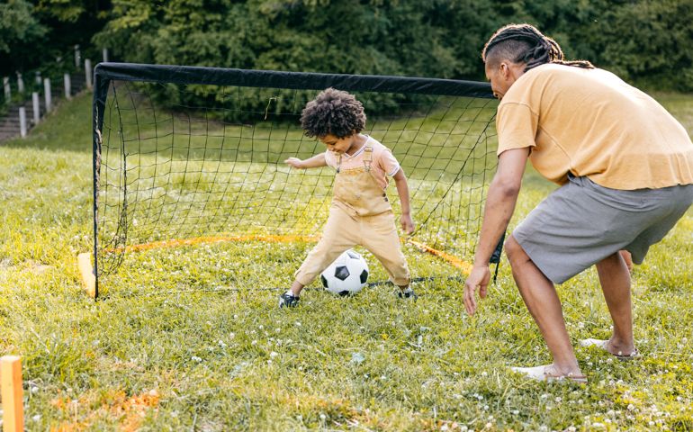 Scoring a goal. Dad and son playing soccer during their day trip together