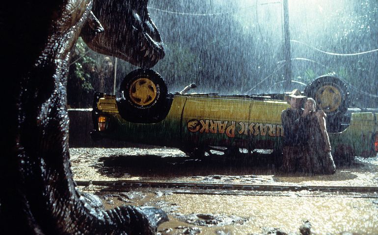 A t-rex approaches the flipped truck in a scene from the film 'Jurassic Park', 1993.