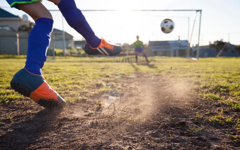 Close up action of boy, aged 14, taking a penalty kick in a football match