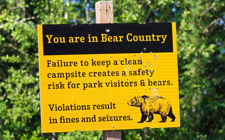 A bullet riddled yellow you are in bear country warning sign.