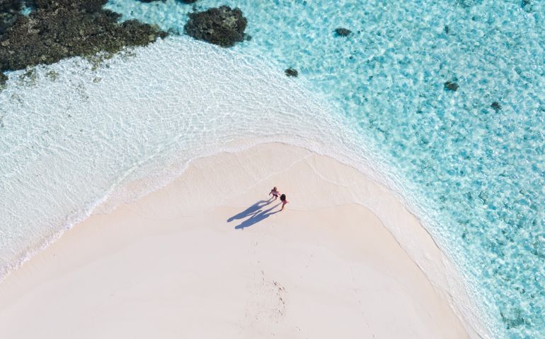 Aerial drone view of adult couple on a sandy beach,