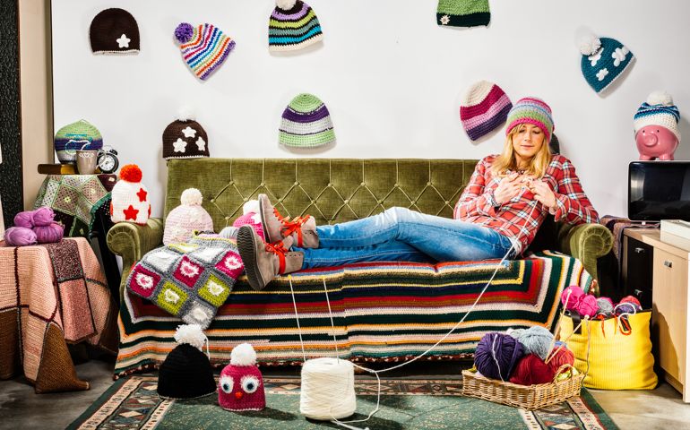 Young woman knitter portrait on couch with winter hats