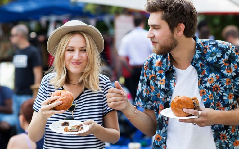 Couple eating burgers at food market