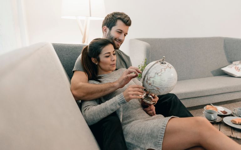 Couple relaxing on couch at home looking at globe