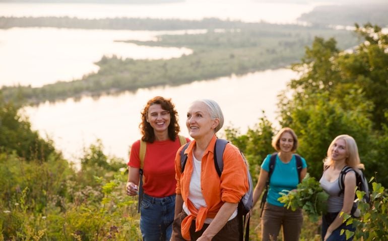 multi generation a group of women friends with backpacks hiking in nature and spending time together. travel tourism concept. Outdoor activities on weekends.