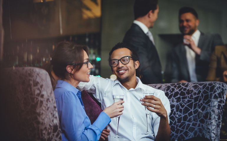 Couple enjoying a glass of champagne after work together at a bar.