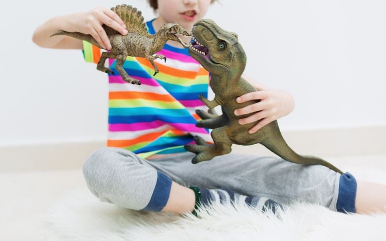 a little boy playing dinosaur toys