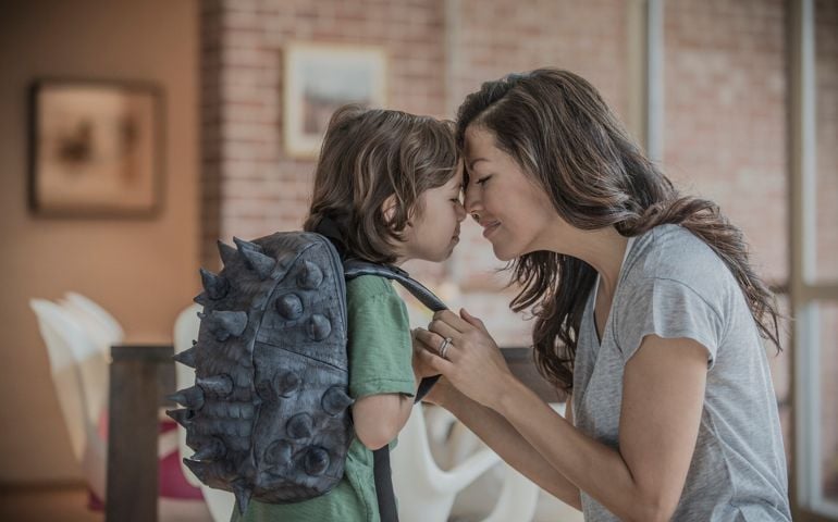 Mother rubbing noses with son wearing spiky back
