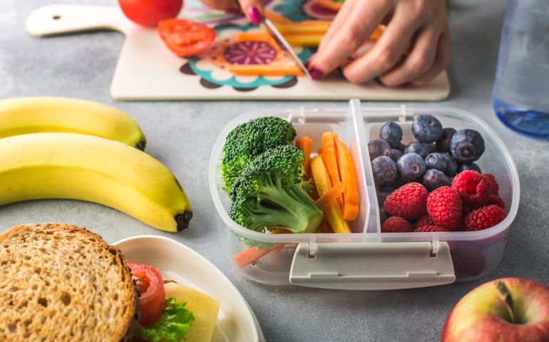 Mother giving healthy lunch for school hands