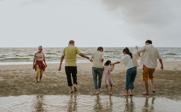 Holding hand with Unity Thai modern family traveling the sea on weekend with positive emotion, Southeast Asian traveling together