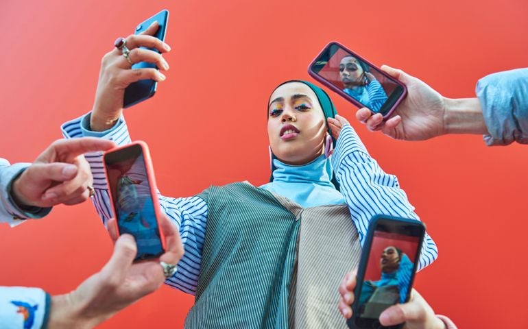 Young woman having picture taken by multiple smartphones.