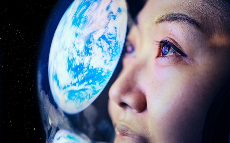 A woman wearing a helmet looking at Earth from space. (Earth image provided by NASA)
