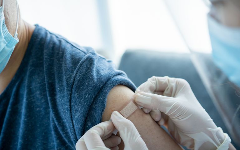 Doctor preparing a dose of vaccine for injection at patient left arm close up with copyspace. Healthcare and medical service concept. COVID-19 or coronavirus cure vaccine injection.