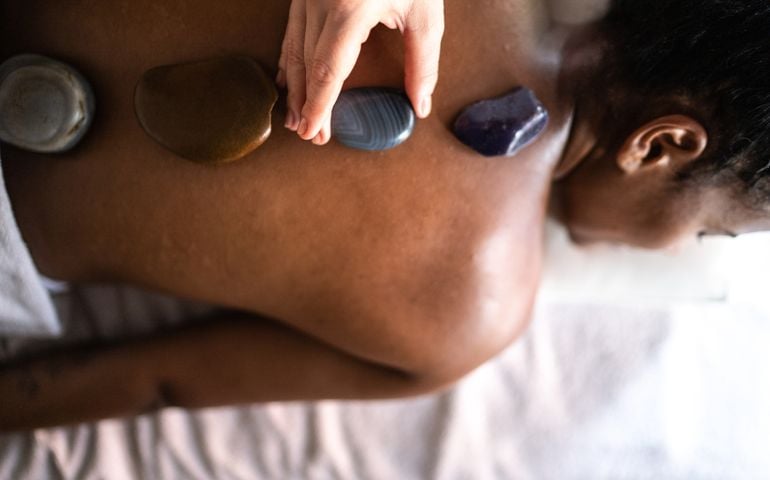 Therapist putting hot stones on woman's back at a spa