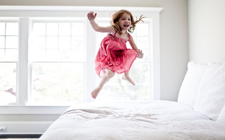 girl jumping on bed