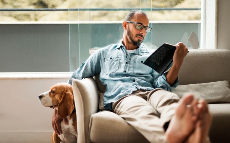 man relaxing reading a book on his couch