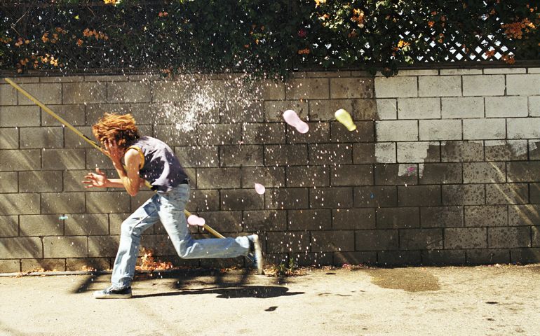 Boy (13-15) in water fight, running from water balloons