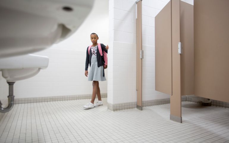Eleven-year-old girl enters a bathroom cautiously.