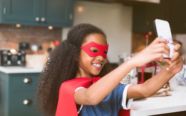 little girl in superhero costume taking a selfie