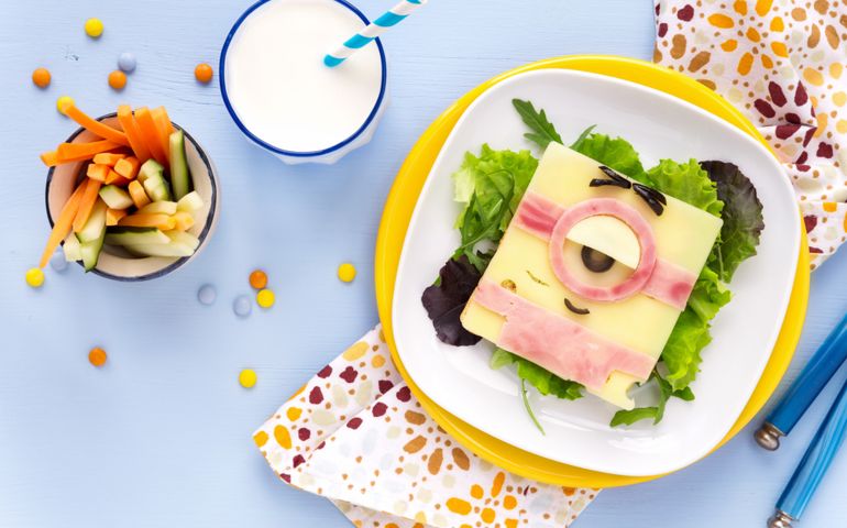 cute Minion shaped sandwich made of ham and cheese served with salad leaves for healthy lunch
