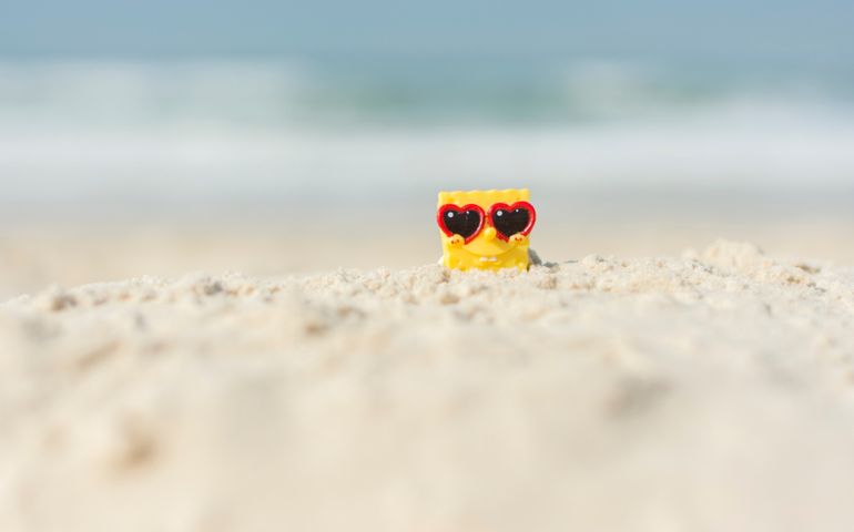 SpongeBob SquarePants relaxing on the beach with heart sunglasses.
