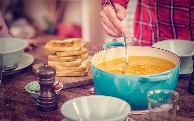 Eating delicous chicken soup with carrots, onions and parsnips. The soup is served in a bowl with creme fresh and grilled toast.