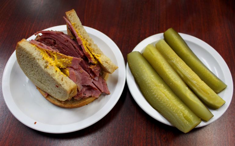 Smoked meat sandwich and pickles at Lester's Deli in Montreal, Quebec, Canada. Montreal smoked meat is a kosher deli meat product made by salting and curing beef brisket with spices. It is typically served on sliced rye bread with mustard. It is more peppery than New York style pastrami.