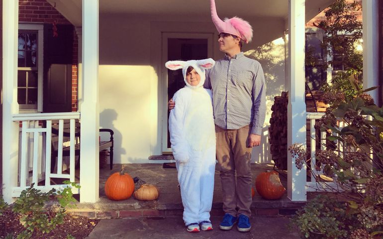Portrait of a boy dressed in a rabbit costume with his father dressed as a pink flamingo ready for an evening of trick or treating on Halloween.