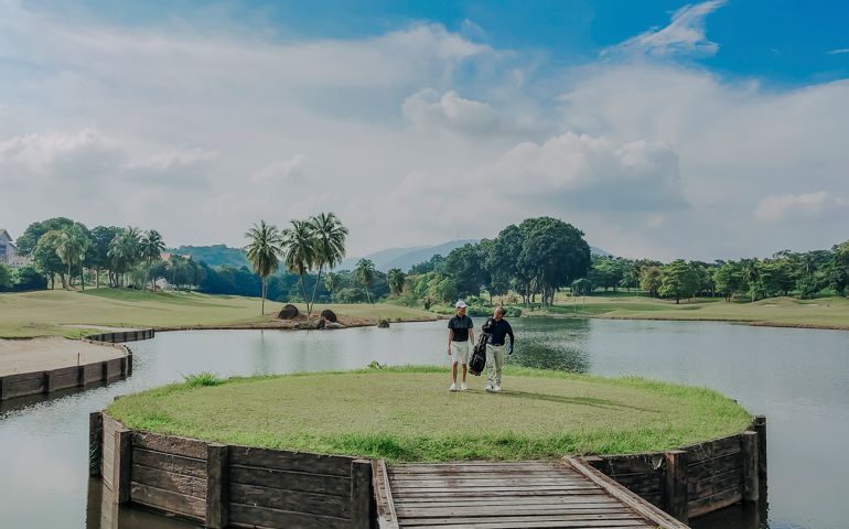 golfer playing golf in golf course in melaka, malaysia walking toward carrying golf set